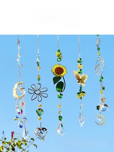 Detail of golden moon and flower suncatchers with faceted crystal prisms against blue sky