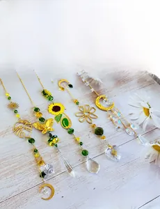 Detail of five gold suncatchers with butterfly and moon designs on a wooden background