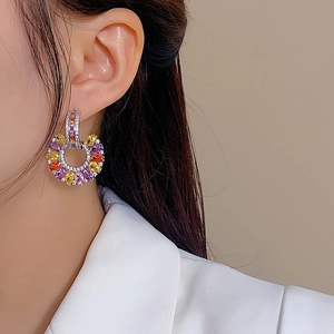 Close-up of model wearing C-shaped earrings with colorful zirconia stones and silver finish