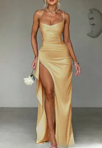 Detail of elegant gold satin evening dress with draped neckline and high leg slit