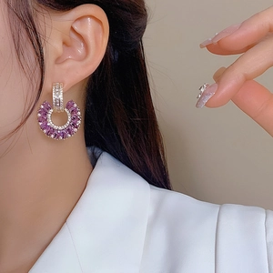 Close-up of model wearing lavender crystal C-shaped fan earrings with pavé zircon