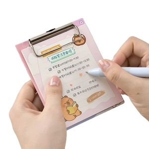 Pink A6 clipboard with cute bear notepad and pen held in hands on white background