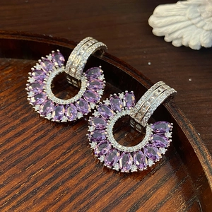 Detail of fan-shaped C-pendant earrings featuring purple gemstones and white zircon stones