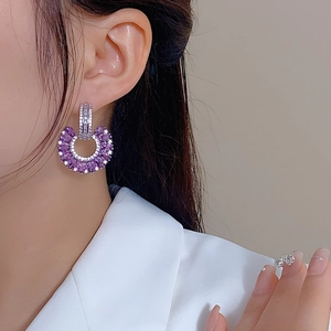 Close-up of C-shaped drop earring with purple marquise stones and pavé zircons on model