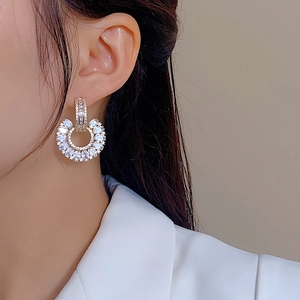 Detailed close-up of gold C-shaped drop earrings with brilliant cubic zirconia clusters