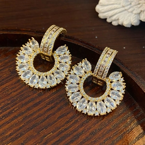 Detail of gold-plated C-shaped earrings with marquise and round cubic zirconia stones