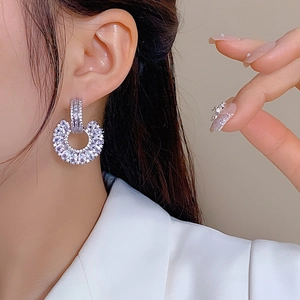 Silver C-shaped hoop earrings with sparkling cubic zirconia on a model wearing a white suit