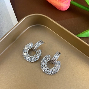 Detailed view of silver C-shaped drop earrings with marquise cubic zirconia on a tray