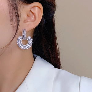 Detailed close-up of C-shaped drop earrings featuring shimmering cubic zirconia pavé