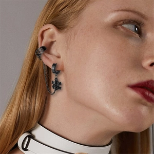 Nahaufnahme eines schwarzen Punk-Ohrring-Sets mit Totenkopf und Kette an einem Model