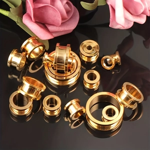 Macro-opname van gepolijste gouden roestvrijstalen ear tunnels met dubbele rand op zwart