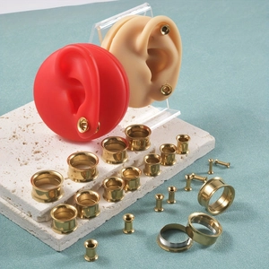 Set de dilatadores dorados de acero inoxidable mostrados en modelos de orejas profesionales