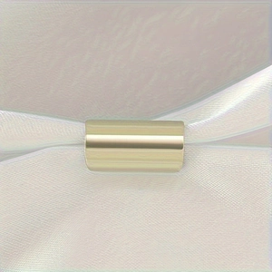 Polished gold cylindrical stainless steel ear cuff clip on a soft white silk background