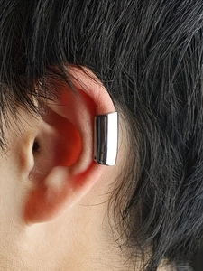 Close-up of polished silver stainless steel ear cuff clip on a person's ear