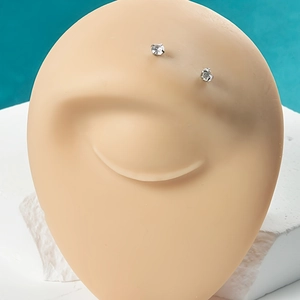 Détail de piercings de sourcils en acier et zircon blanc sur un modèle en silicone
