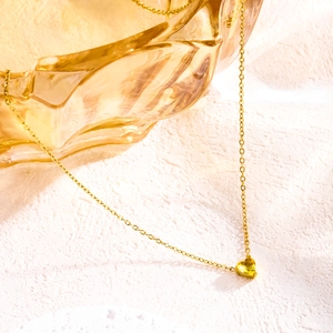 Macro detail of gold heart pendant with yellow birthstone on a delicate chain