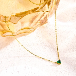 Close-up of heart-shaped green birthstone pendant on gold stainless steel chain