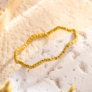 Minimalistischer goldener Wellenring mit Hammerschlag-Textur auf weißem Stein-Dekor