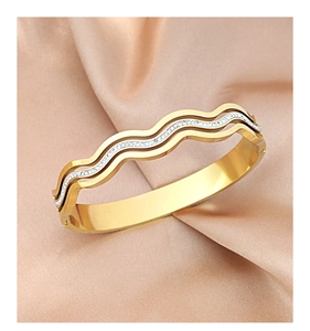 Detail of rose gold wavy bangle featuring paved small crystals on silk fabric background