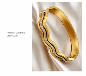 Macro detail of rose gold wavy bangle with white rhinestones on champagne silk fabric