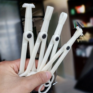 Set of four white plastic disposable body piercing clamps with various clamp head shapes