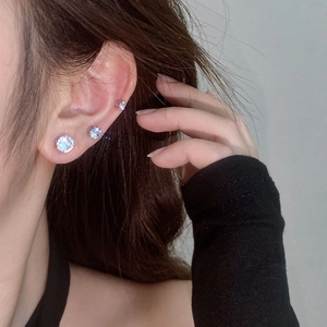 Detailed view of three sizes of round-cut magnetic stud earrings with silver setting on ear