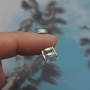 Primer plano de un pendiente magnético de circonita cuadrada con engaste de garras de plata