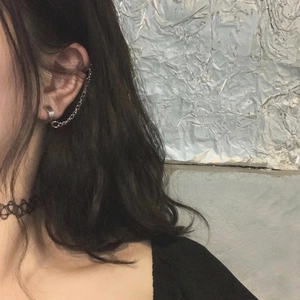 Detail view of silver stainless steel chain earring with ear cuff worn by a model