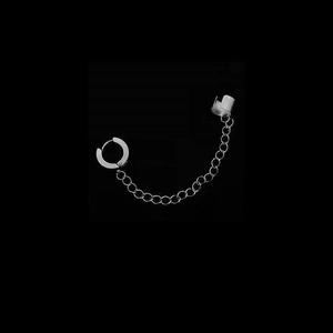 Detail of silver stainless steel earring featuring a hoop, chain, and ear cuff on black background