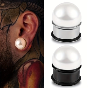 Detailed view of large pearl ear plugs in gold finish on human ear with O-ring seal