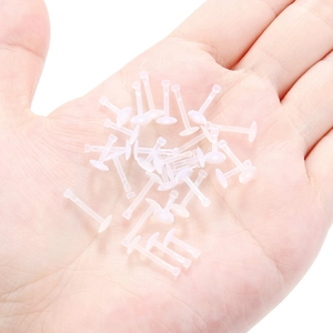 Close-up of flexible acrylic piercing retainers held in hand for size scale and detail