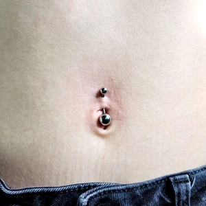 Polished stainless steel double ball belly button ring shown on navel piercing