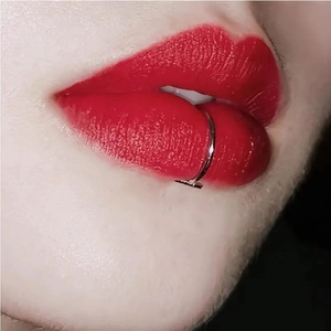 Vista macro de un piercing de aro labial en acero inoxidable plateado sobre un modelo