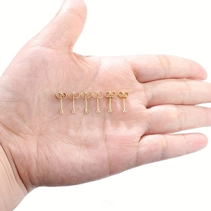 Detailed palm view of six golden stainless steel stud earrings with butterfly backings