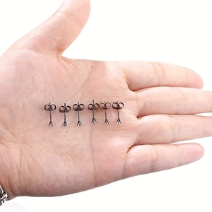 Detailed macro view of black stainless steel stud earrings held in hand for size