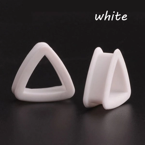 Macro detail of white triangle silicone ear gauges showing hollow saddle design