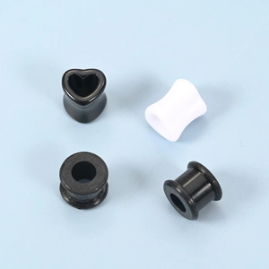 Detailliertes Set aus schwarzen herzförmigen und zylindrischen Silikon-Ohrplugs auf Blau