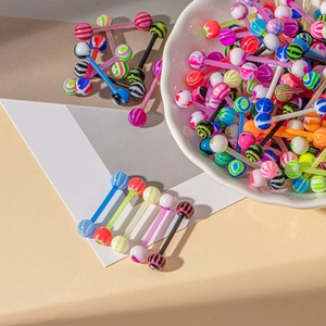 Gros plan de piercings de langue en acrylique colorés avec motifs rayés et à pois