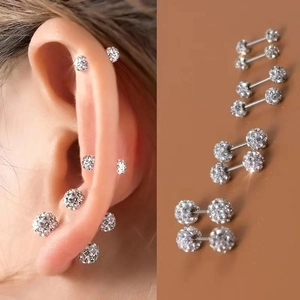 Detailed view of silver stainless steel crystal ball stud earrings on human ear and flat surface