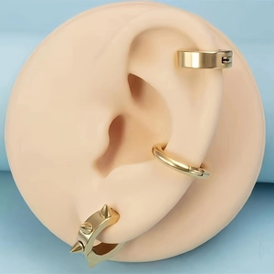 Primer plano de tres clips de oreja de acero inoxidable dorado estilo punk en un modelo