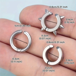 Juego de tres ear cuffs de acero inoxidable plateado con diseños de pinchos y aros en mano