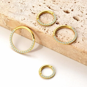 Detailed set of four gold-plated nose rings with CZ pavé settings on stone background