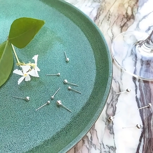 Classic silver ball stud earrings set displayed on a marble surface with natural decor