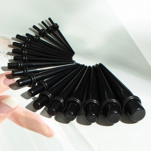 Macro view of 18 black acrylic ear tapers in various sizes with silicone O-rings