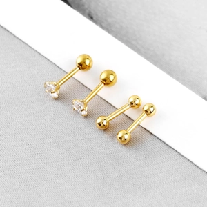 Detailed macro view of four golden barbell piercings with clear zircons and metal spheres