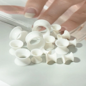 Detailed close-up of white acrylic ear gauges in various sizes showing smooth matte finish