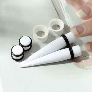 Macro view of white acrylic ear stretching kit including tapers, plugs and tunnels