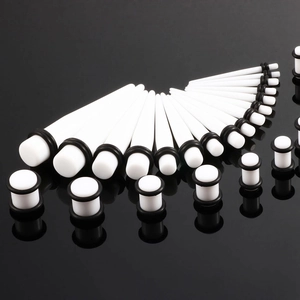 Dehnungstab Set aus weißem Acryl mit Plugs und Tapers auf schwarzem Untergrund