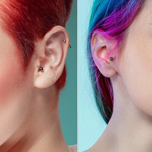 Vue détaillée de piercings en acier chirurgical argent et noir portés au tragus et hélix