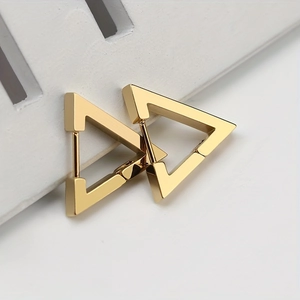 Detailed close-up of golden triangular geometric earrings on a white jewelry stand